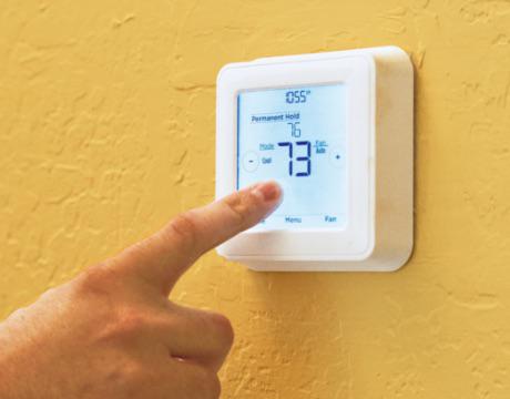 adult male finder on a thermostat adjusting the temperature