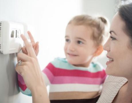 close up of a woman and child adjusting a thermostat